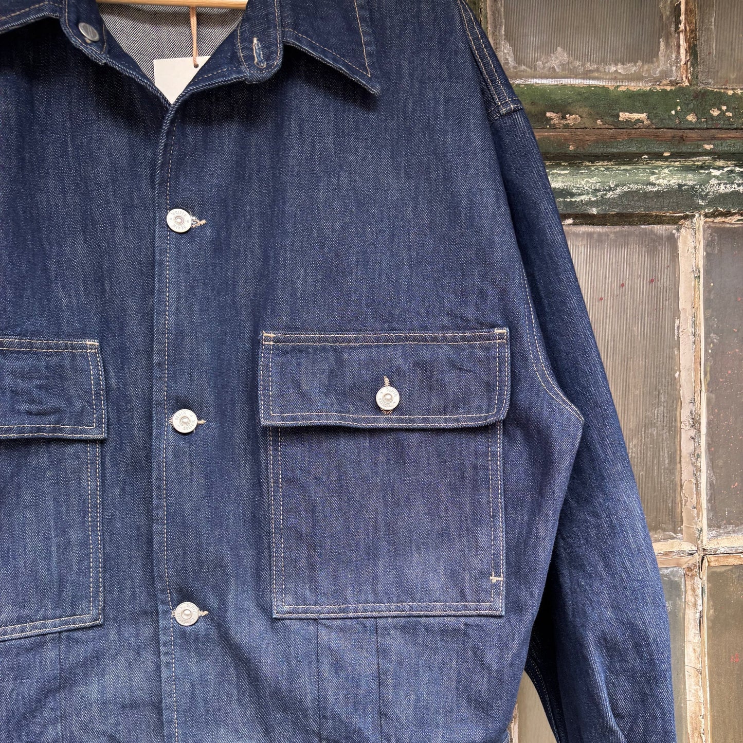 Blue denim jacket with button details against a rustic wooden background