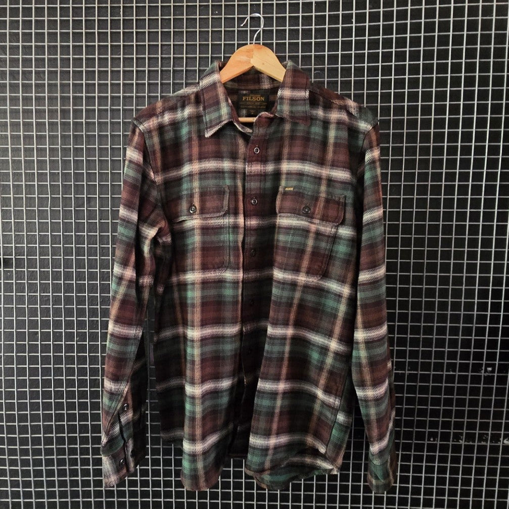Plaid shirt hanging on a grid wall with bags and shoes around