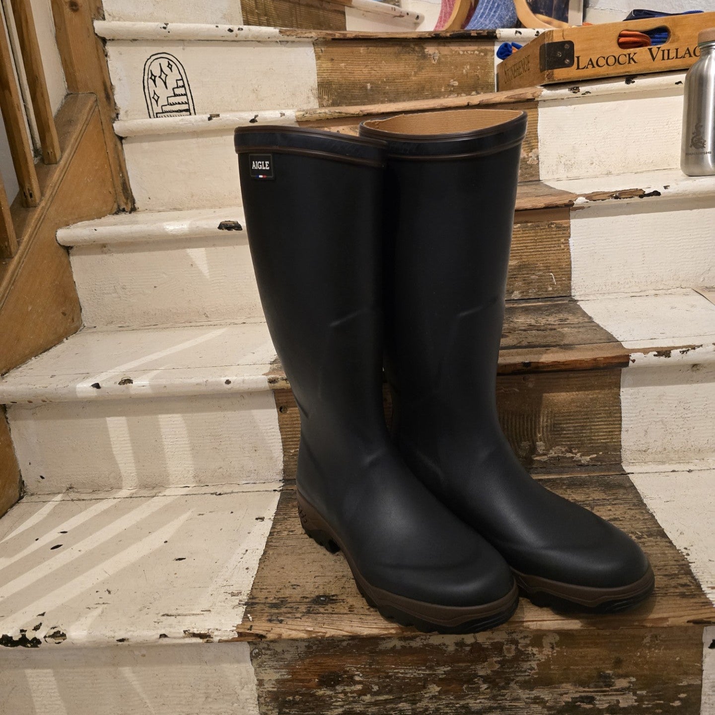 Pair of black rubber boots on a wooden staircase