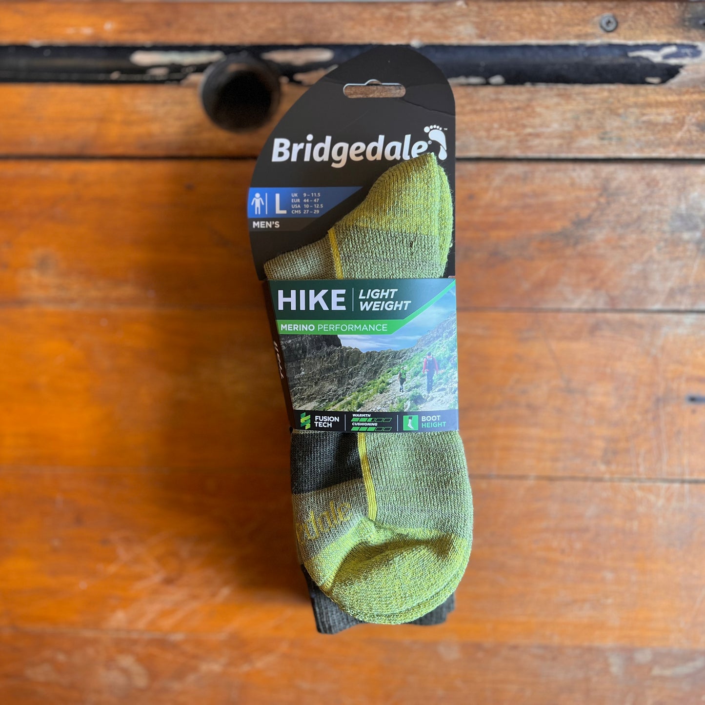 A light green walking sock on a wooden background.