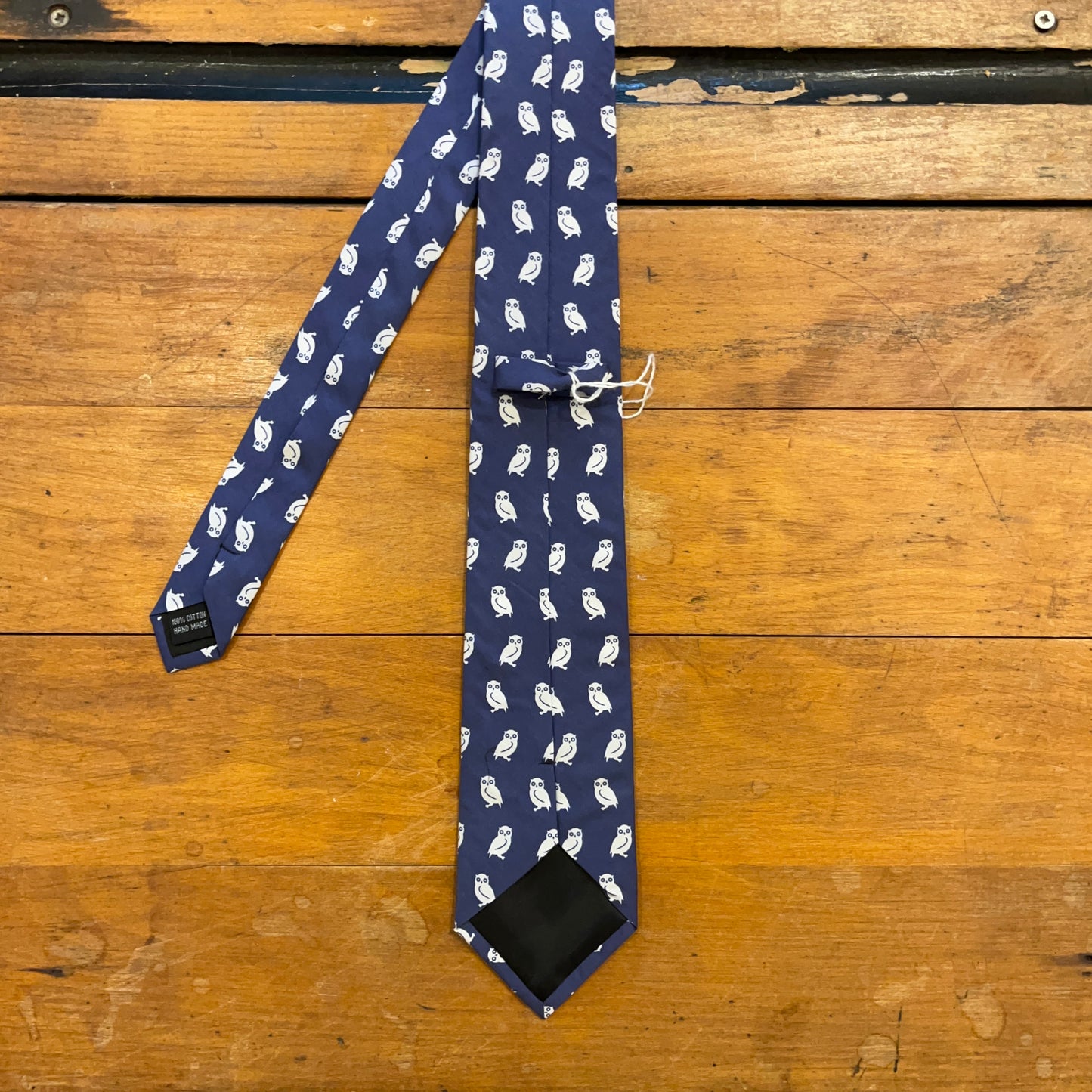 reverse of blue cotton tie with owl pattern on boards