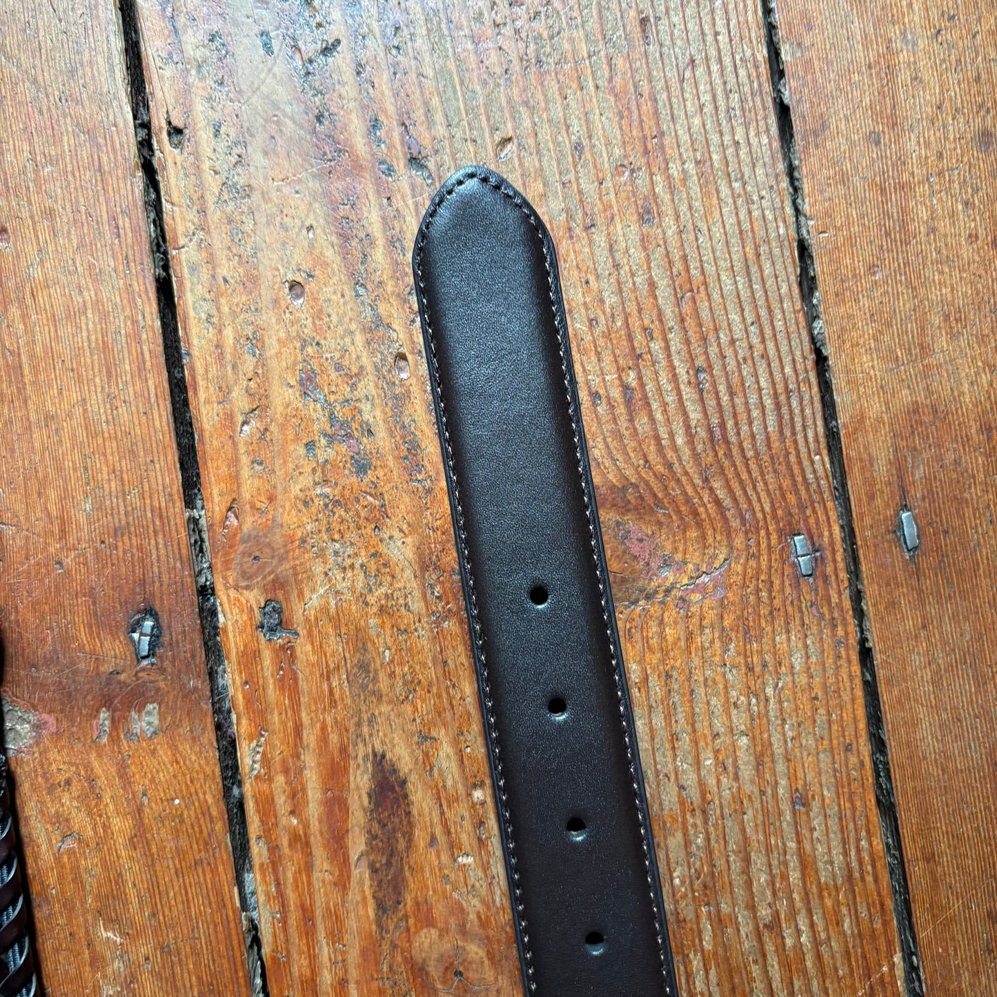 Black leather belt on a wooden surface