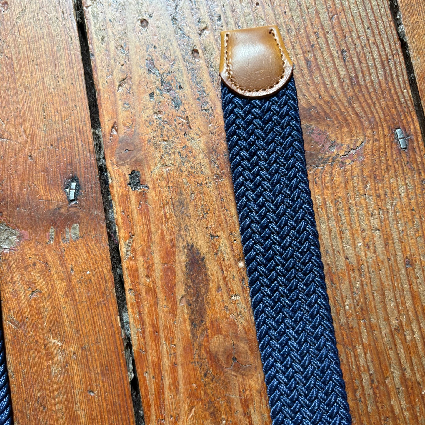 Blue braided strap with brown leather buckle on a wooden surface