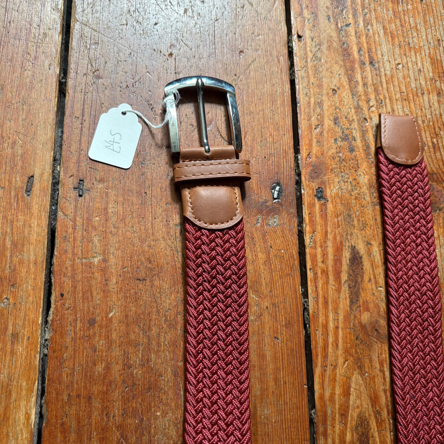 Brown belt with woven red strap on a wooden surface