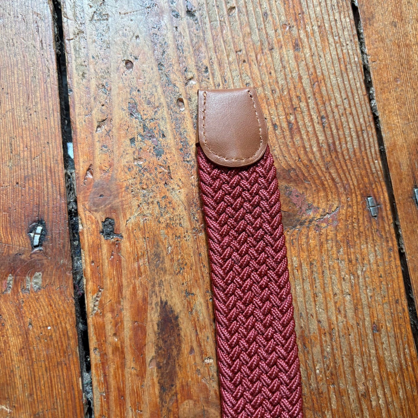 Red braided strap with brown leather end on a wooden surface