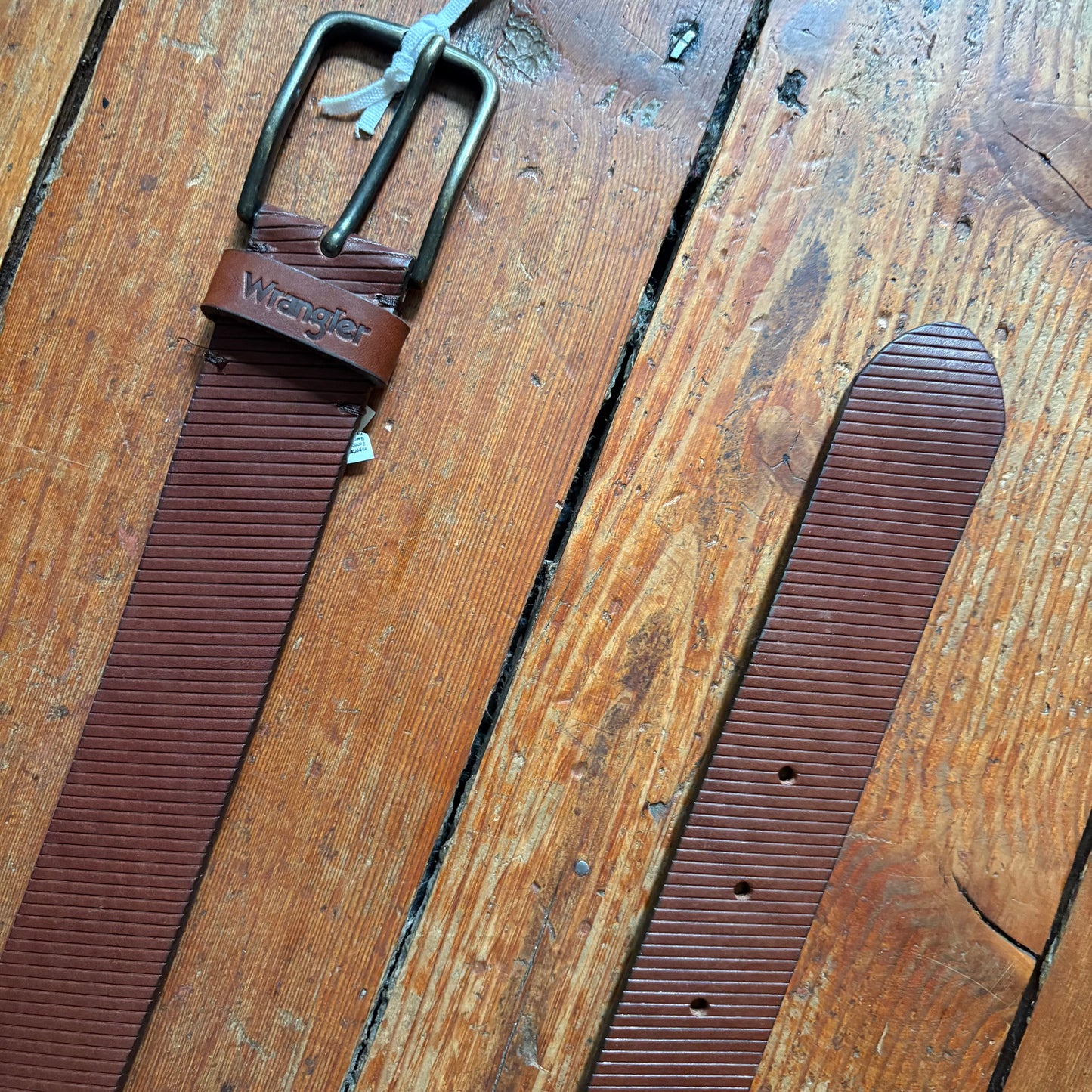 Brown leather belt with metal buckle on a wooden surface