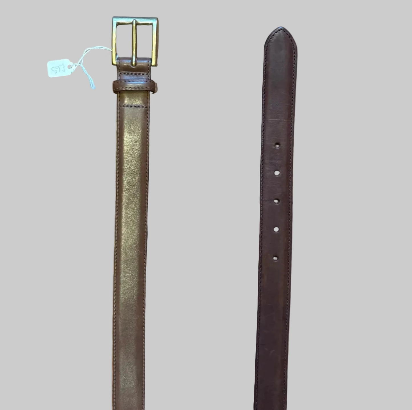 Brown leather belt with brass buckle on a wooden surface