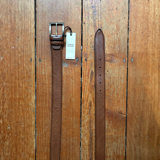 Brown leather belt with a metal buckle on a wooden surface