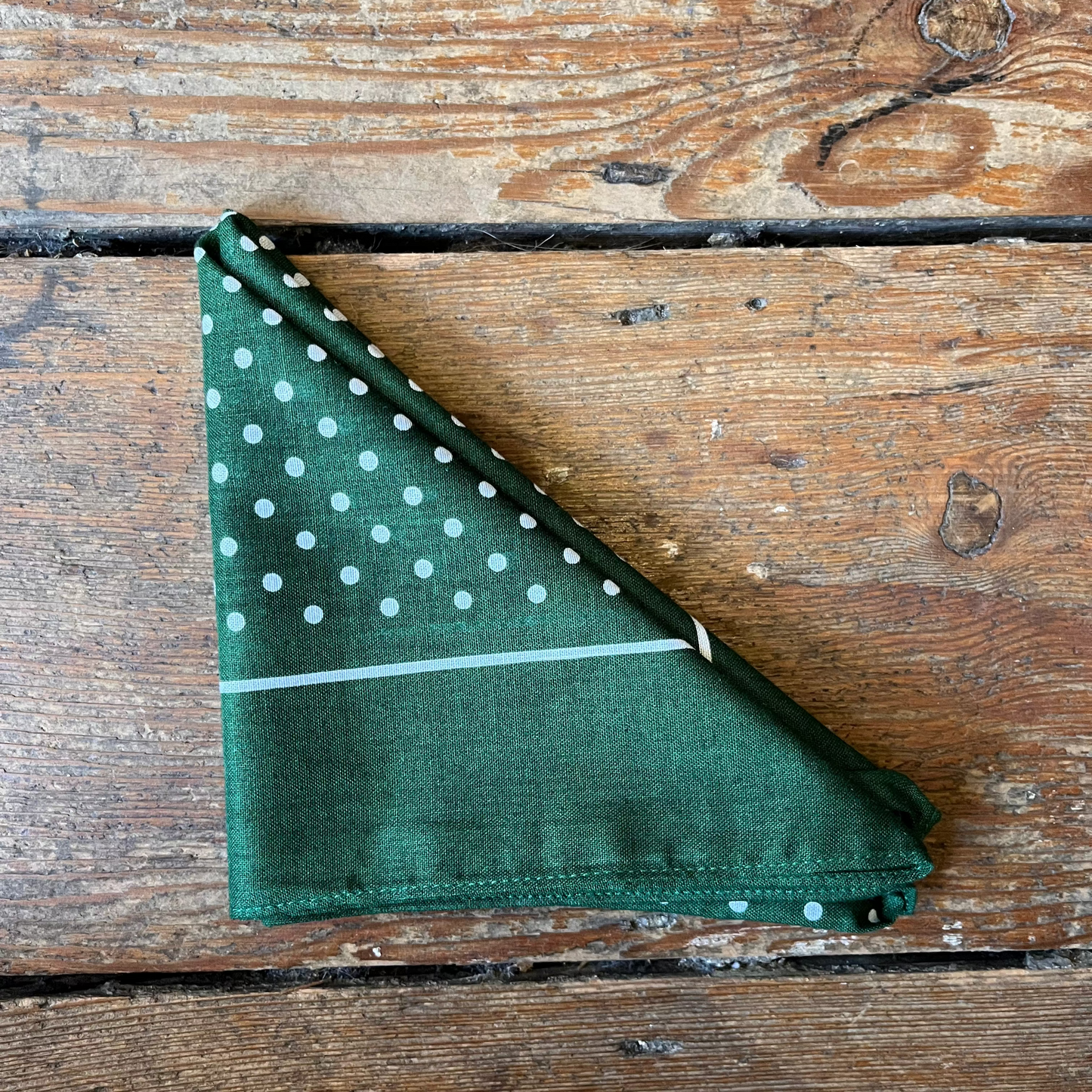 Green fabric with white polka dots on a wooden surface