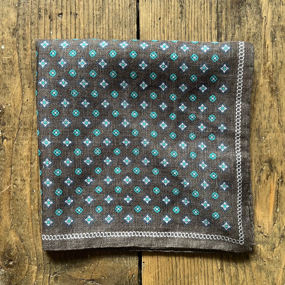 Brown linen folded pocket square with navy and turquoise motif pattern