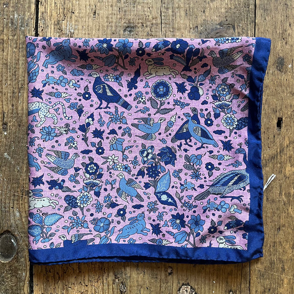 Pink silk pocket square with a pattern of blue birds, rabbits and flowers
