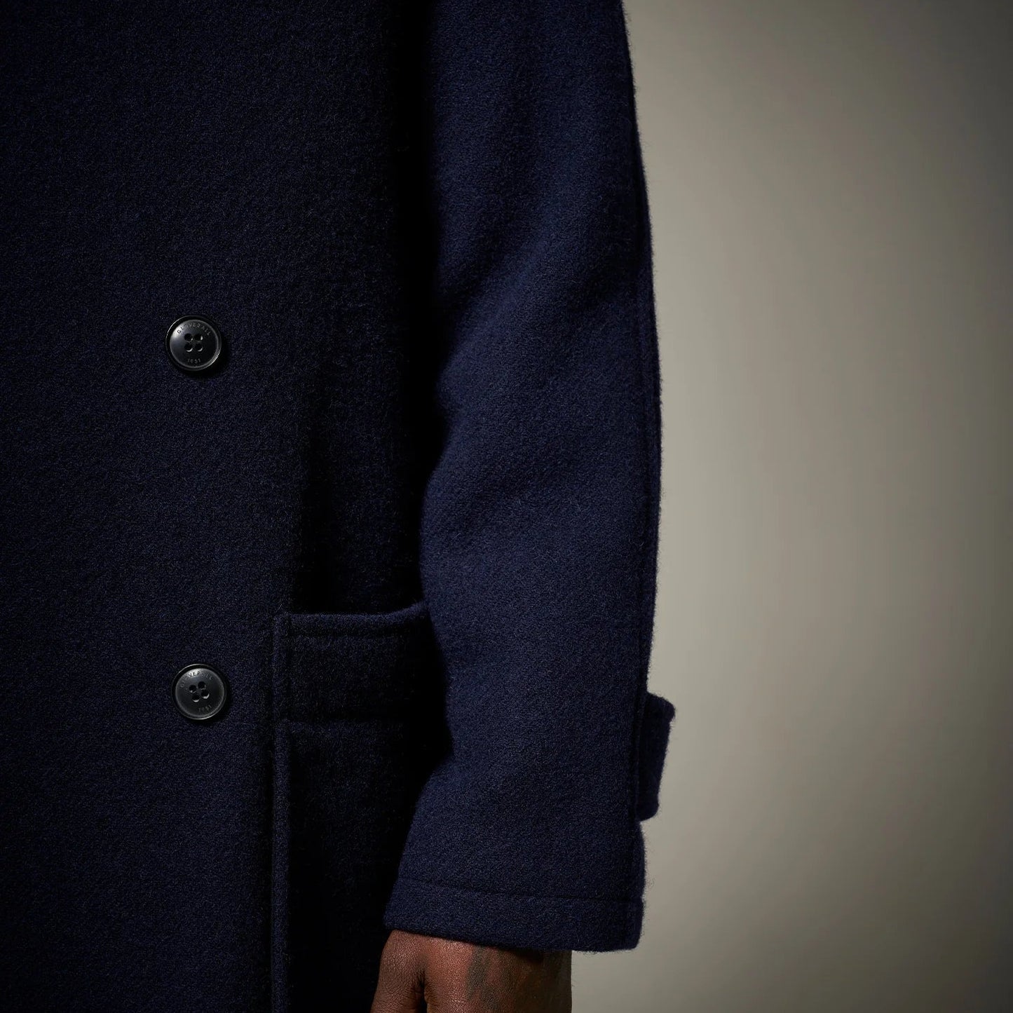 Navy blue coat with button details on a neutral background