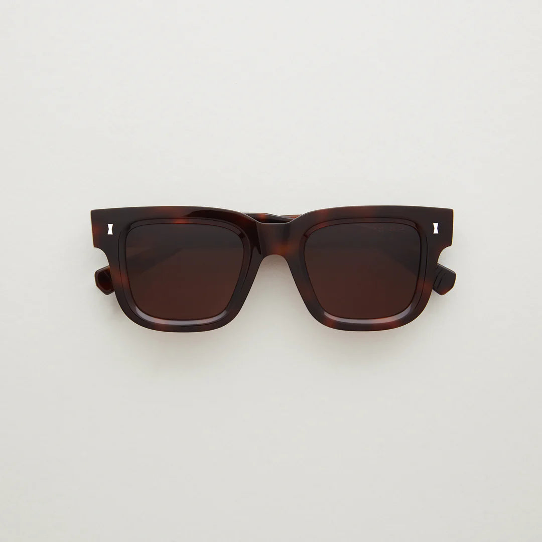 Dark tortoiseshell acetate sunglasses, silver detail in far corner, large rectangular shape. 