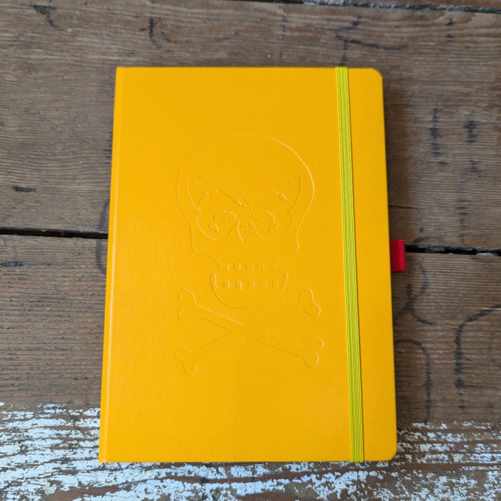 Yellow hard case notebook with matching strap and skull and crossbones logo embossed on the front