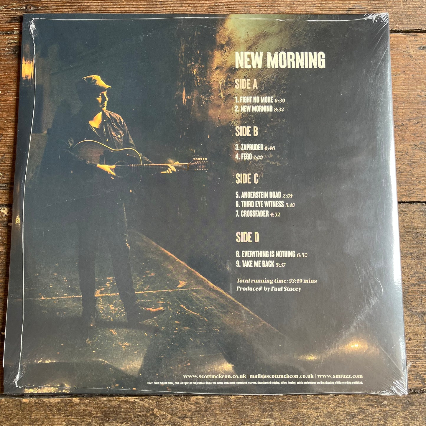 Vinyl record cover with album art and tracklist on a wooden surface