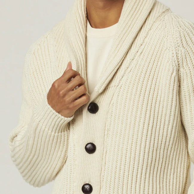 Man wearing a cream-colored cardigan with buttons on a plain background