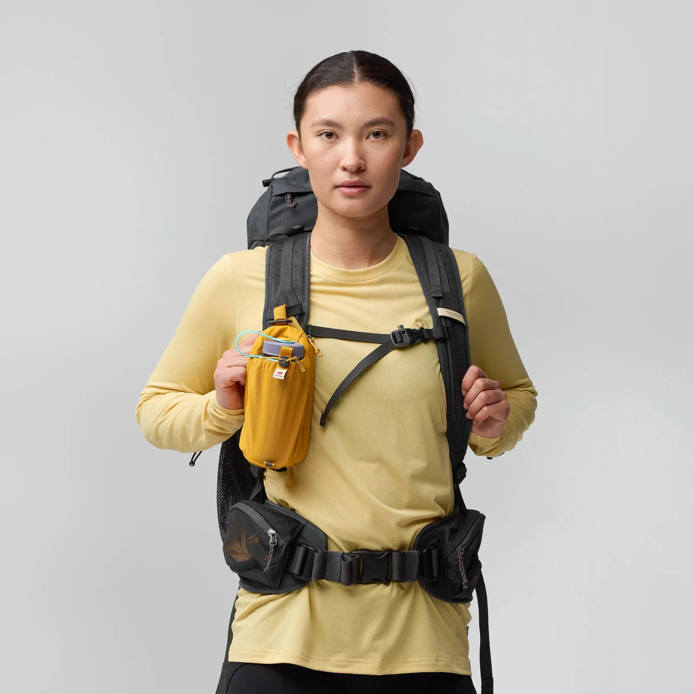 A woman wears a backpack with a water bottle holder