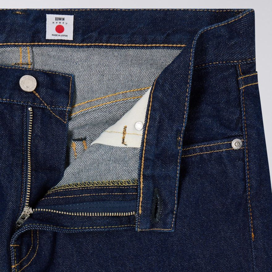 Close-up of blue denim jeans with a brand label on a light gray background