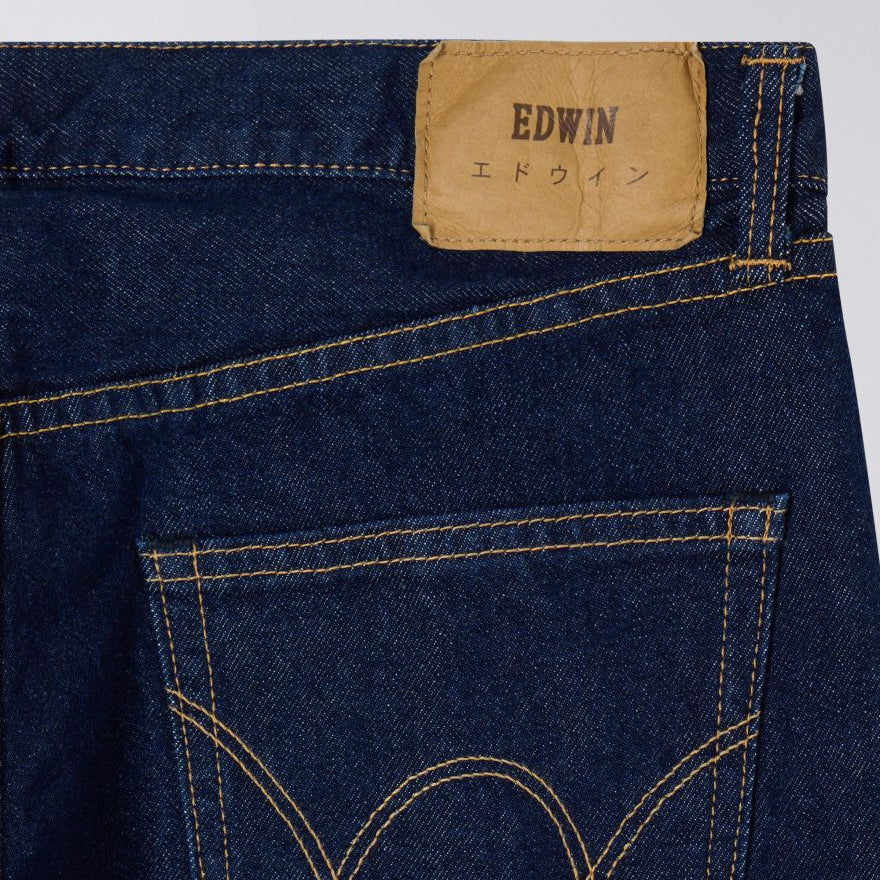 Close-up of a blue denim jeans with a visible Edwin label on a light gray background