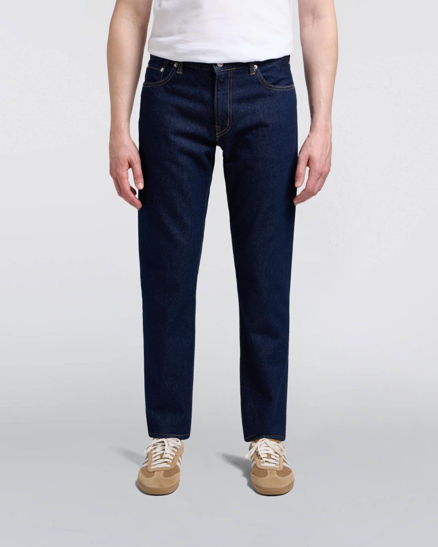 Person wearing dark blue jeans and a white shirt on a light gray background