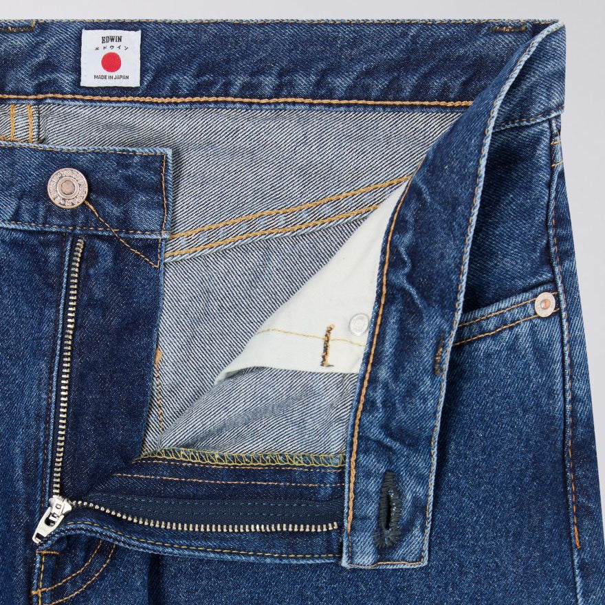 Close-up of blue denim jeans with a brand label on a gray background