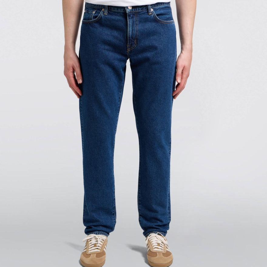 Person wearing blue jeans and a white shirt on a plain background