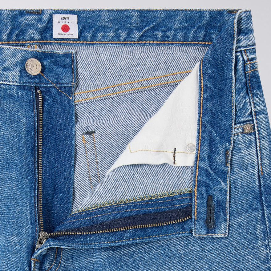 Close-up of blue denim jeans with a brand label on a light gray background