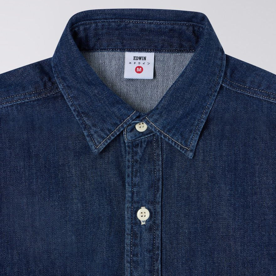Close-up of a blue denim shirt with a brand label on a light gray background