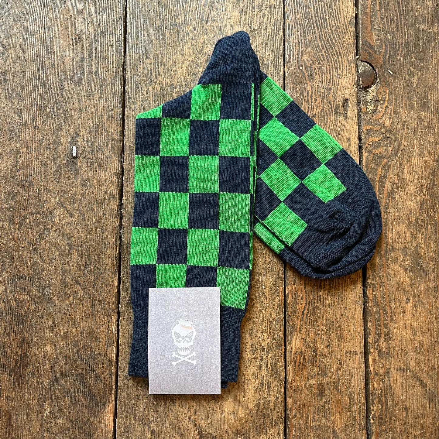Green and navy checkered socks with a brand label on a wooden surface