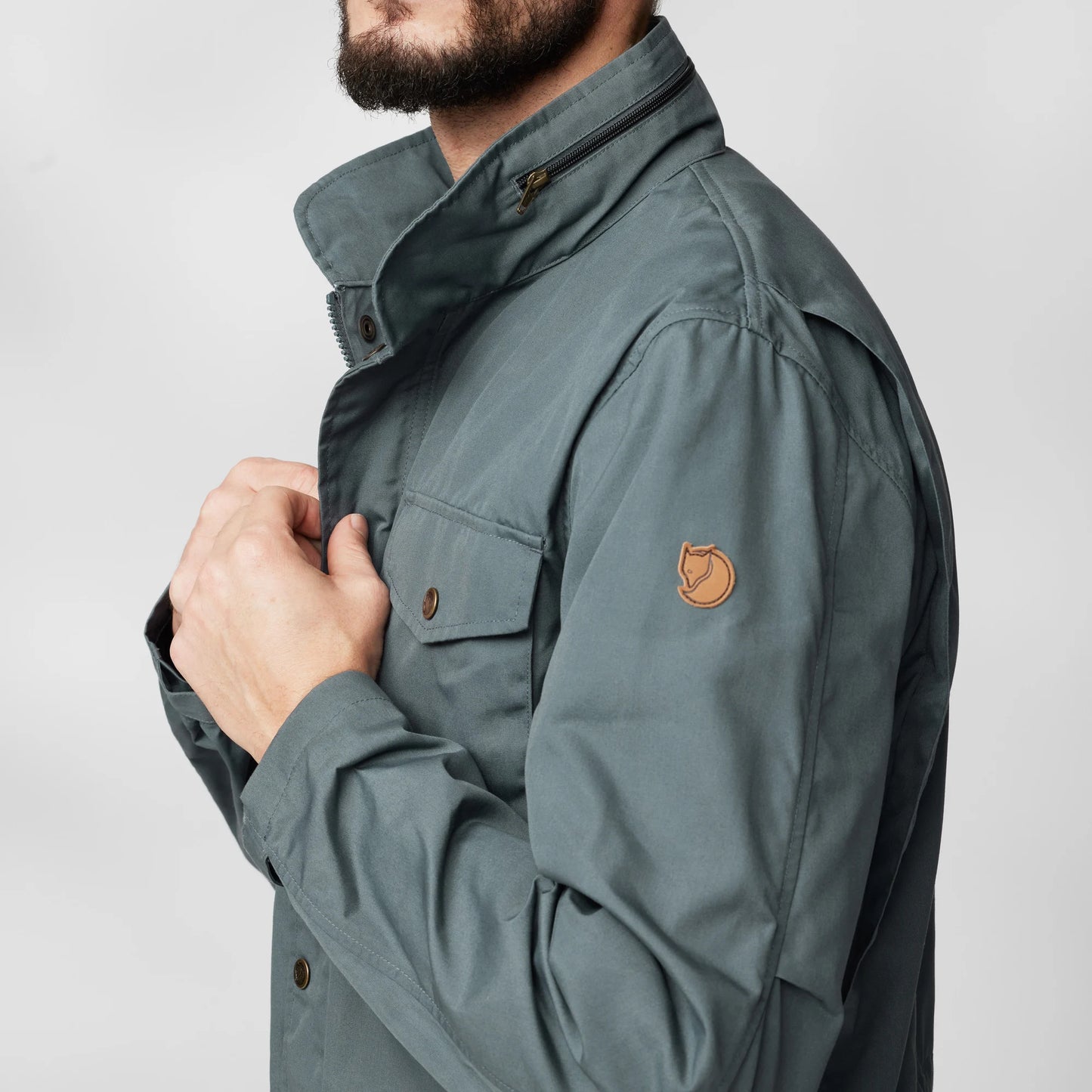 Close up of shoulder and fjallraven logo of Fjällräven's Räven Jacket in Dusk/ grey/ green