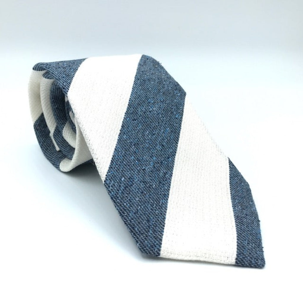 A luxury silk tie designed by and handmade exclusively for Regent. White and slate blue stripes, flecked with sky blue, overlay a tie woven in a mixture of cotton and silk for a textured, cosy, bohemian feel. 