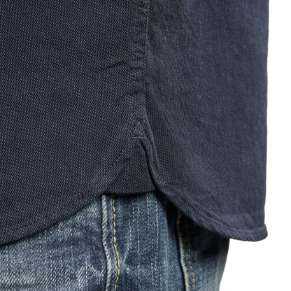 Close-up of a dark navy blue shirt hem tucked into blue jeans, showing the fabric texture and contrast stitching.