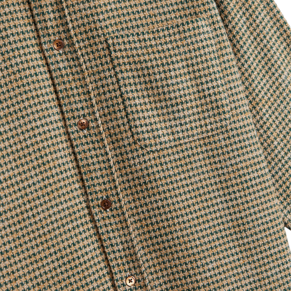 Close-up of a textured houndstooth patterned fabric in beige and dark green, featuring brown buttons down the front placket.