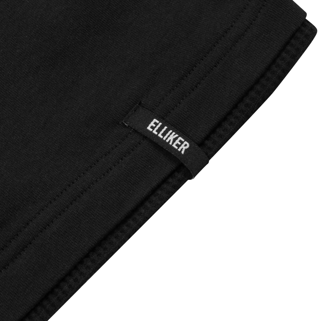 Close-up of a black knit fabric item folded over, showing a small black fabric tag with the brand name 'ELLIKER' in white text, against a white background.