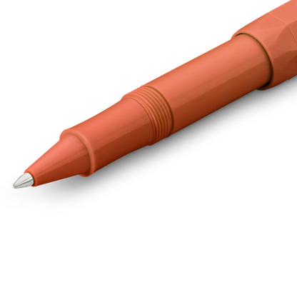 A close-up of a terracotta orange ballpoint pen showing the tip, clicker, and textured barrel against a clean white background.