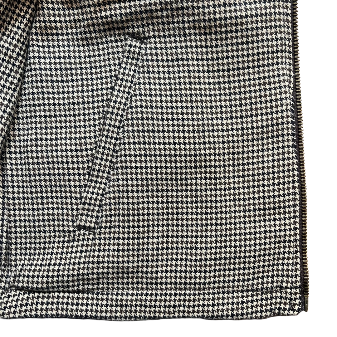 Close-up of a black and off-white houndstooth patterned fabric with a diagonal seam and a zipper edge on the right side.