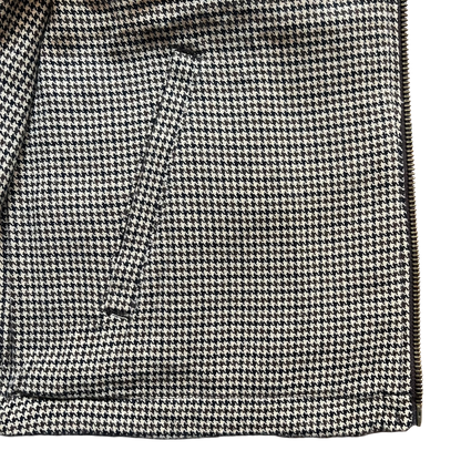 Close-up of a black and off-white houndstooth patterned fabric with a diagonal seam and a zipper edge on the right side.