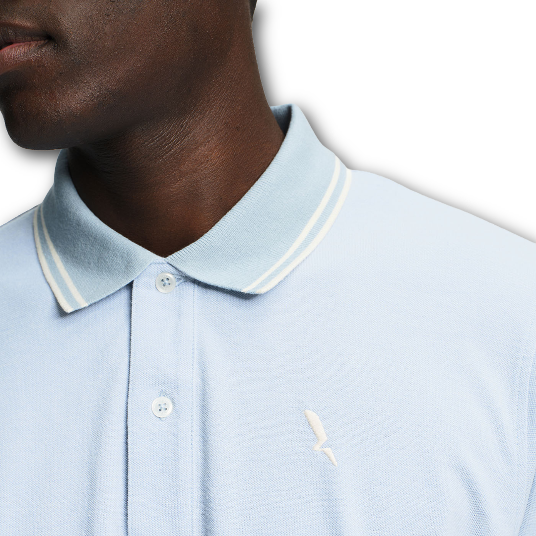 Close up of collar of Aigle light blue polo shirt with white trim worn by a person on a white background sold at Regent in Salisbury