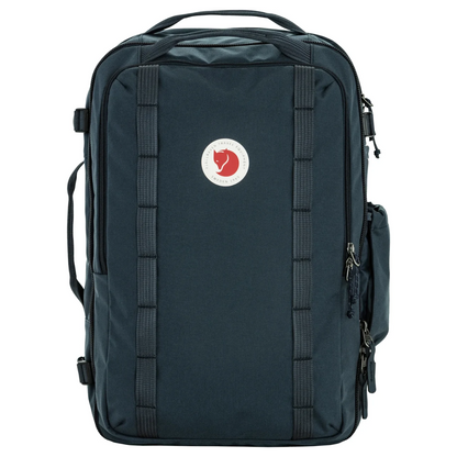 A Fjälken backpack in dark navy blue, featuring a vertical zippered front pocket with a classic red fox logo patch on the front, set against a plain white background.