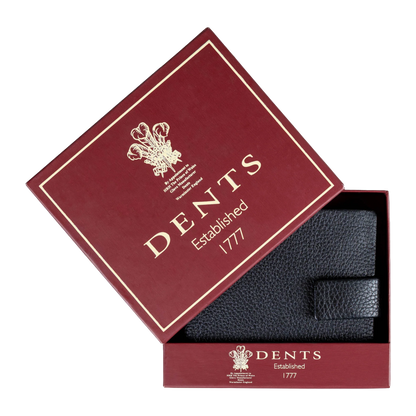 A black textured leather accessory, likely a wallet or pocket square, presented inside an open burgundy DENTS gift box with gold lettering on a white background.
