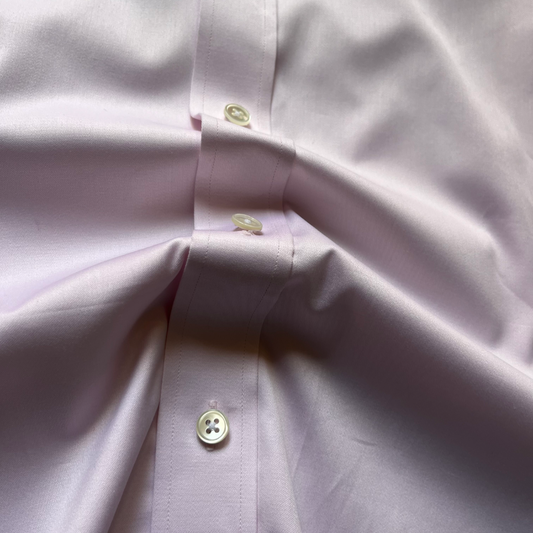 Close-up of a light lavender dress shirt showing the button placket with cream-colored buttons and fine fabric texture.