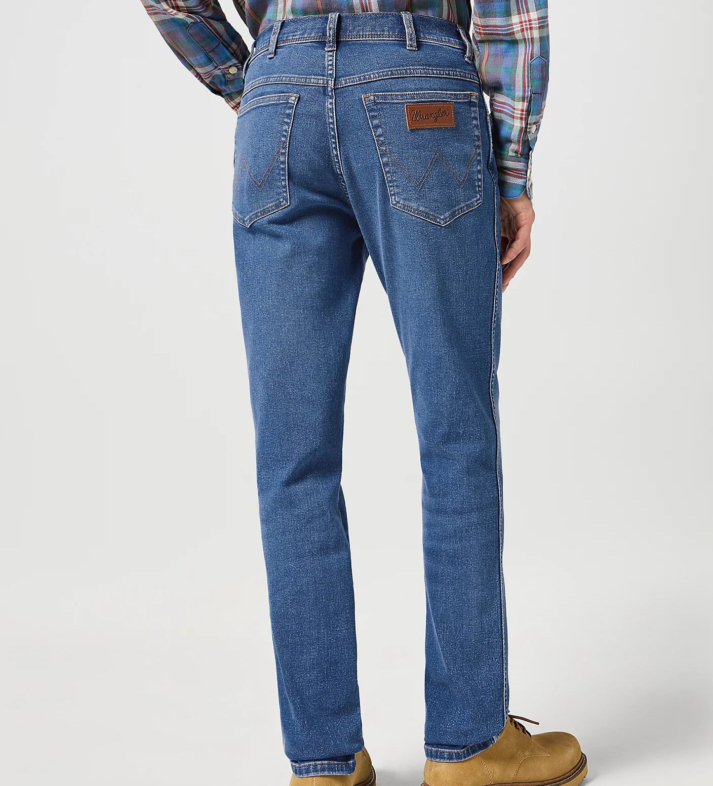 Person wearing blue jeans and a plaid shirt on a white background