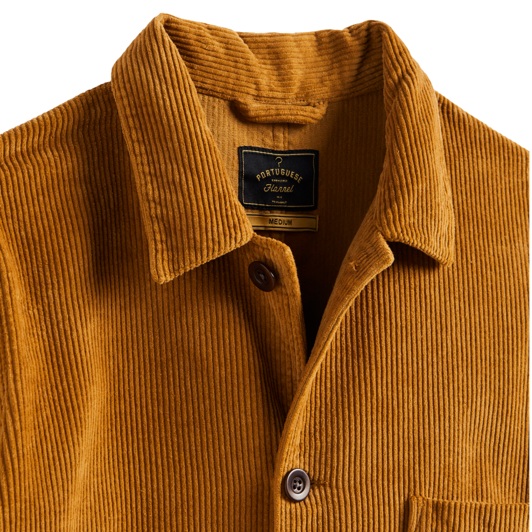 Close-up of a Port Turner corduroy shirt jacket in a warm mustard yellow color, showing the collar, button closure, and interior neck label.