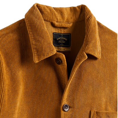 Close-up of a Port Turner corduroy shirt jacket in a warm mustard yellow color, showing the collar, button closure, and interior neck label.