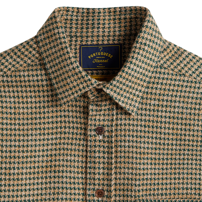 Close-up of a collared button-up shirt with a small-scale houndstooth pattern in beige and dark green. The shirt features a dark blue neck label with gold lettering that reads 'PORTUGUE Houndstooth'.