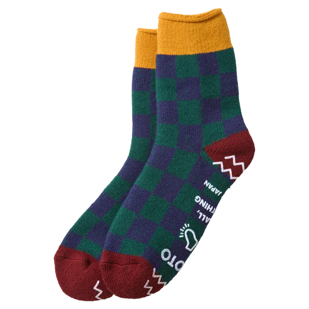 A pair of crew socks with a green and purple checkered pattern, featuring a mustard yellow cuff, red toes and heels, and white graphic text and symbols on the sides.