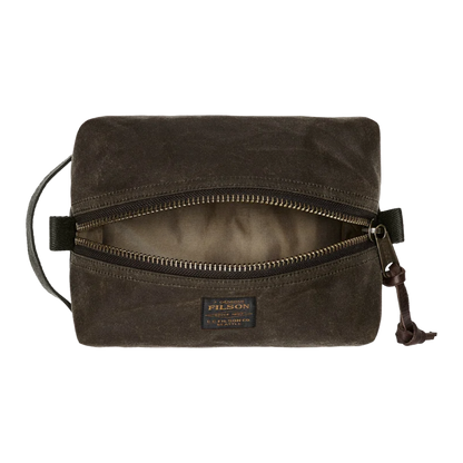 A dark brown Filson waxed canvas pouch with an open top zipper, showing a beige interior lining. The Filson brand label is visible on the front, and a leather zipper pull hangs on the right side against a plain white background.