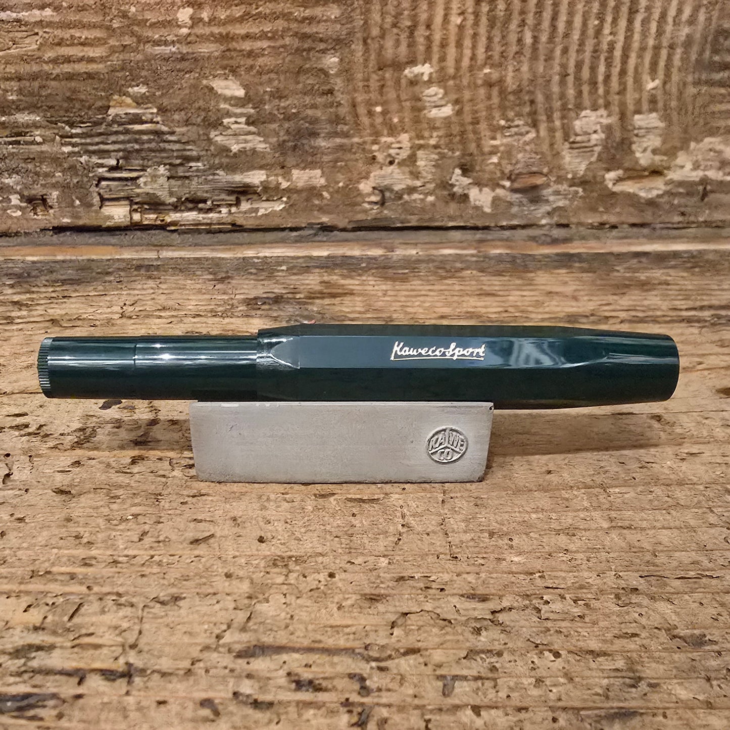 Dark Green Kaweco Pen with lid on on a wooden block and wooden background