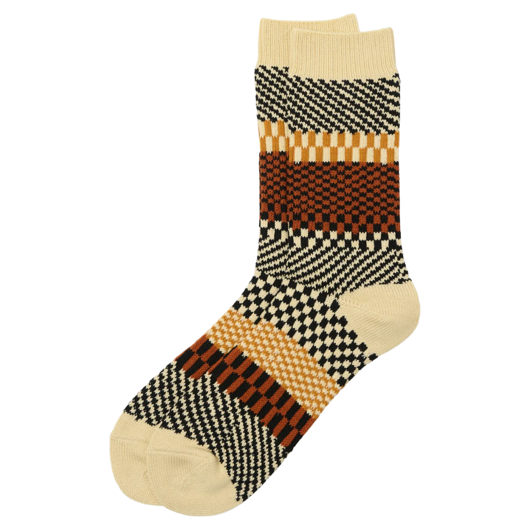 A pair of crew socks with a complex geometric pattern featuring black, brown, and beige checkerboard and striped blocks, shown on a plain white background.