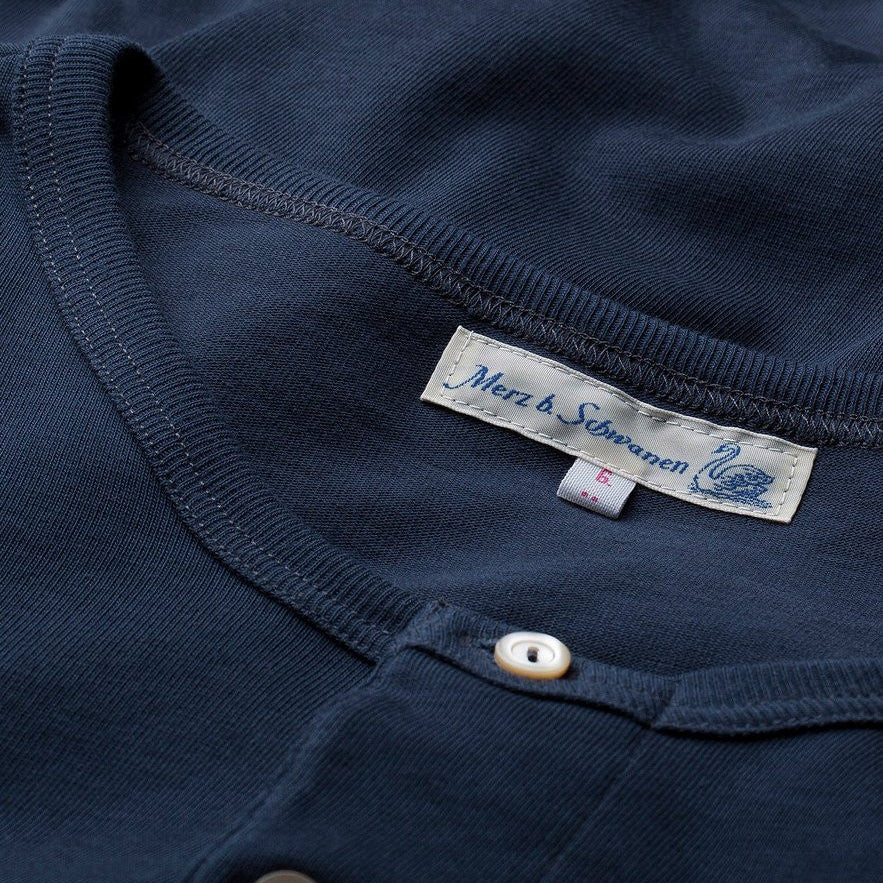 Close-up of a navy blue garment with a brand label on a white background